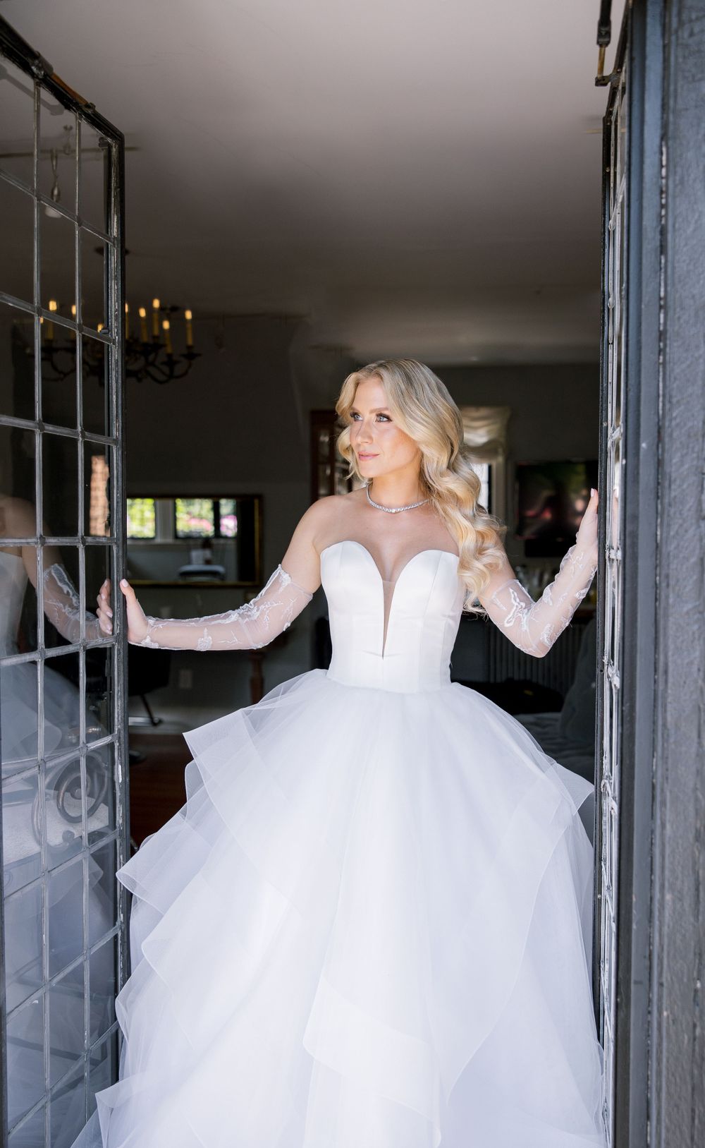 Wedding dress with illusion sleeves and layered tulle skirt shown in doorway.