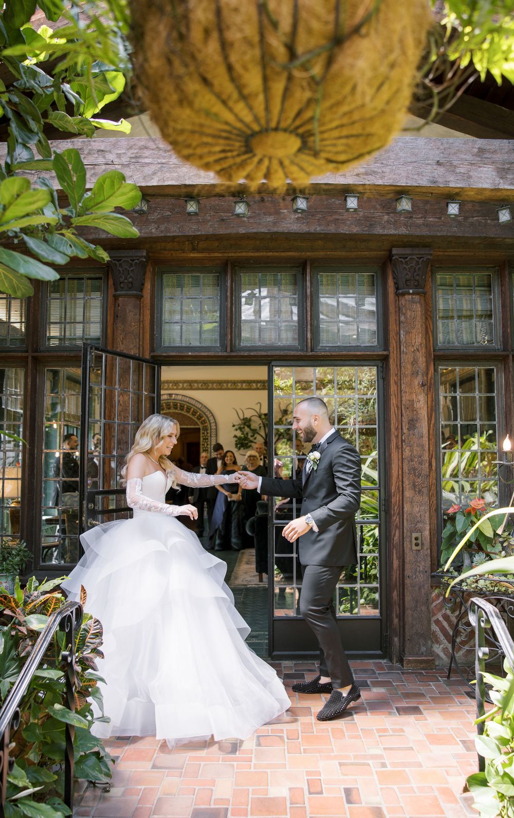 Wedding couple dancing on patio entrance with rustic wooden details and greenery.