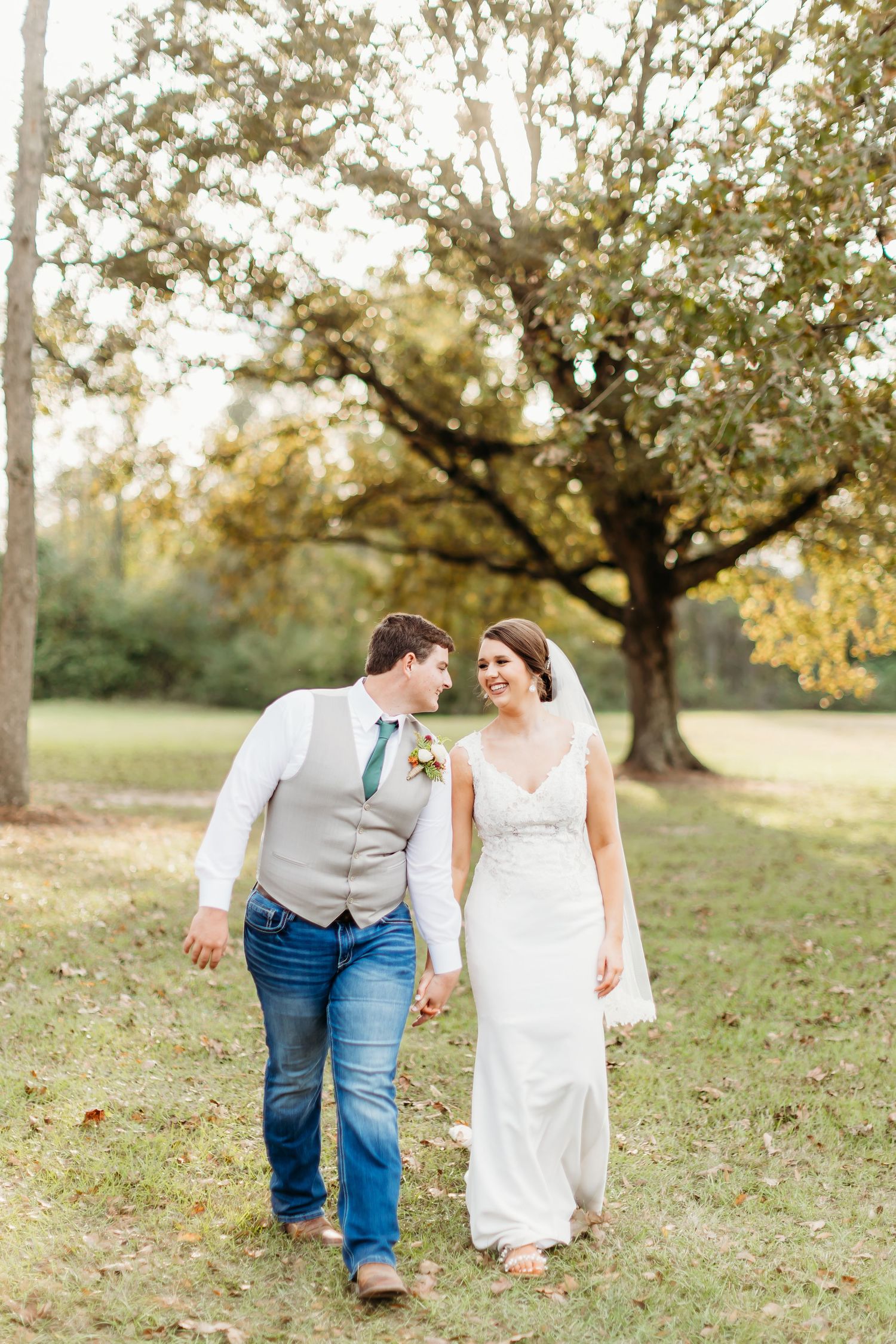 A couple walks together through a scenic autumn orchard during a romantic photo session.