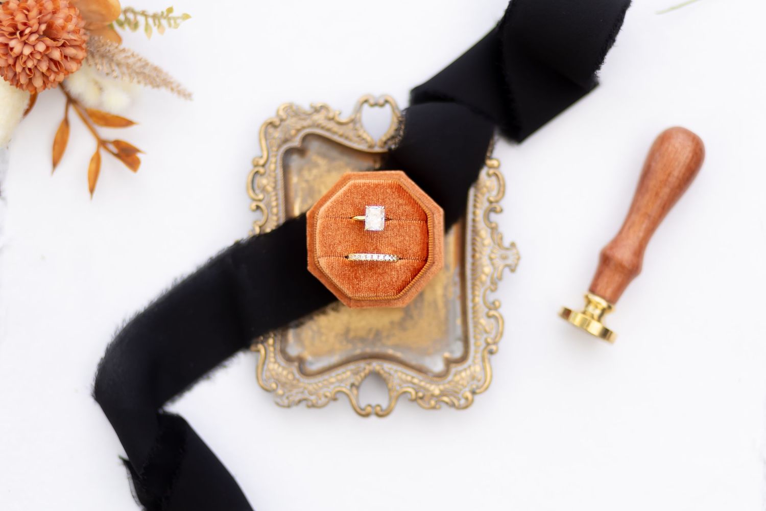 Wedding detail shot of a perfume bottle with black ribbon on vintage tray.