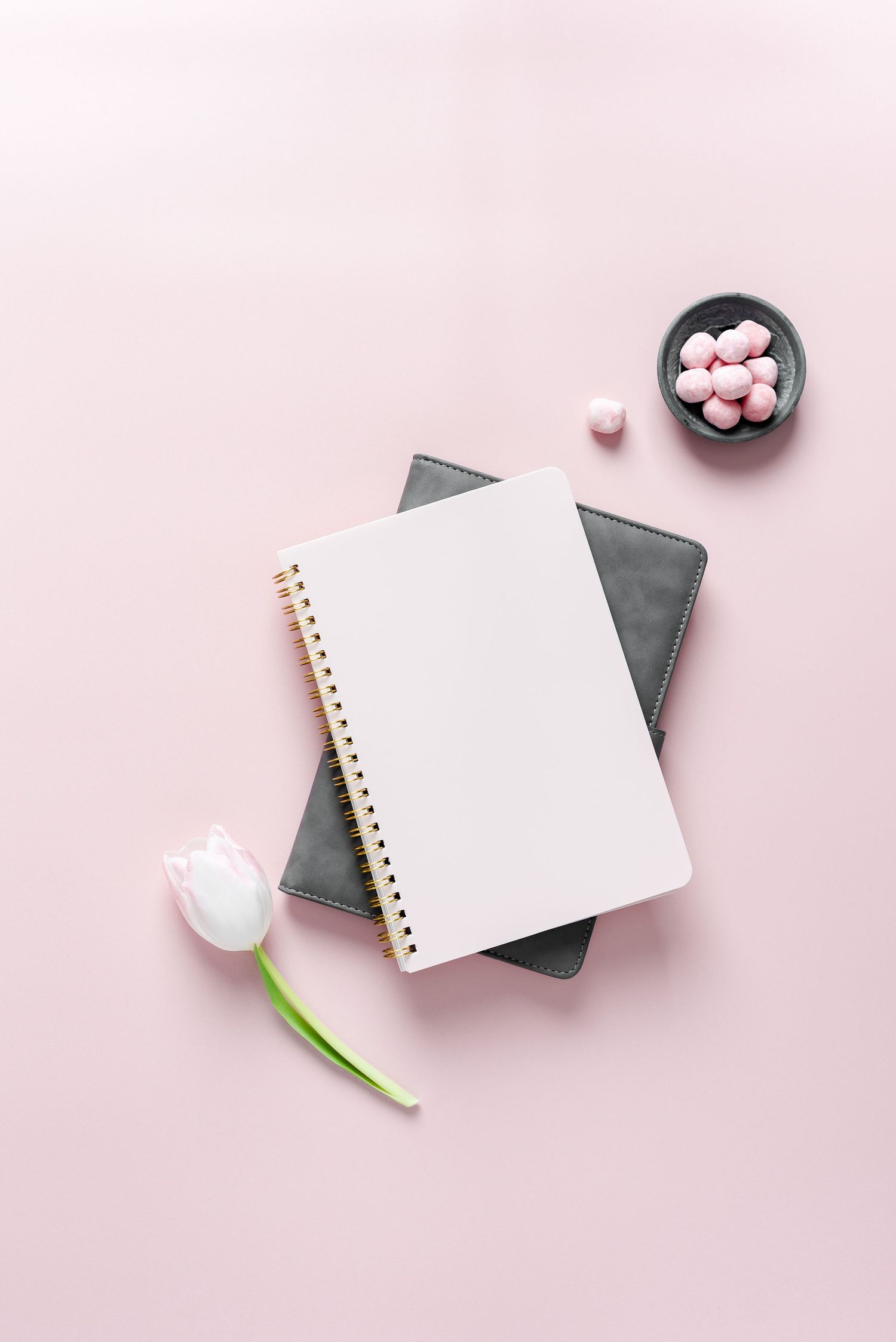 pink journal angled on top of grey journal with pink sweets on a pink backdrop, pretty, feminine and crisp