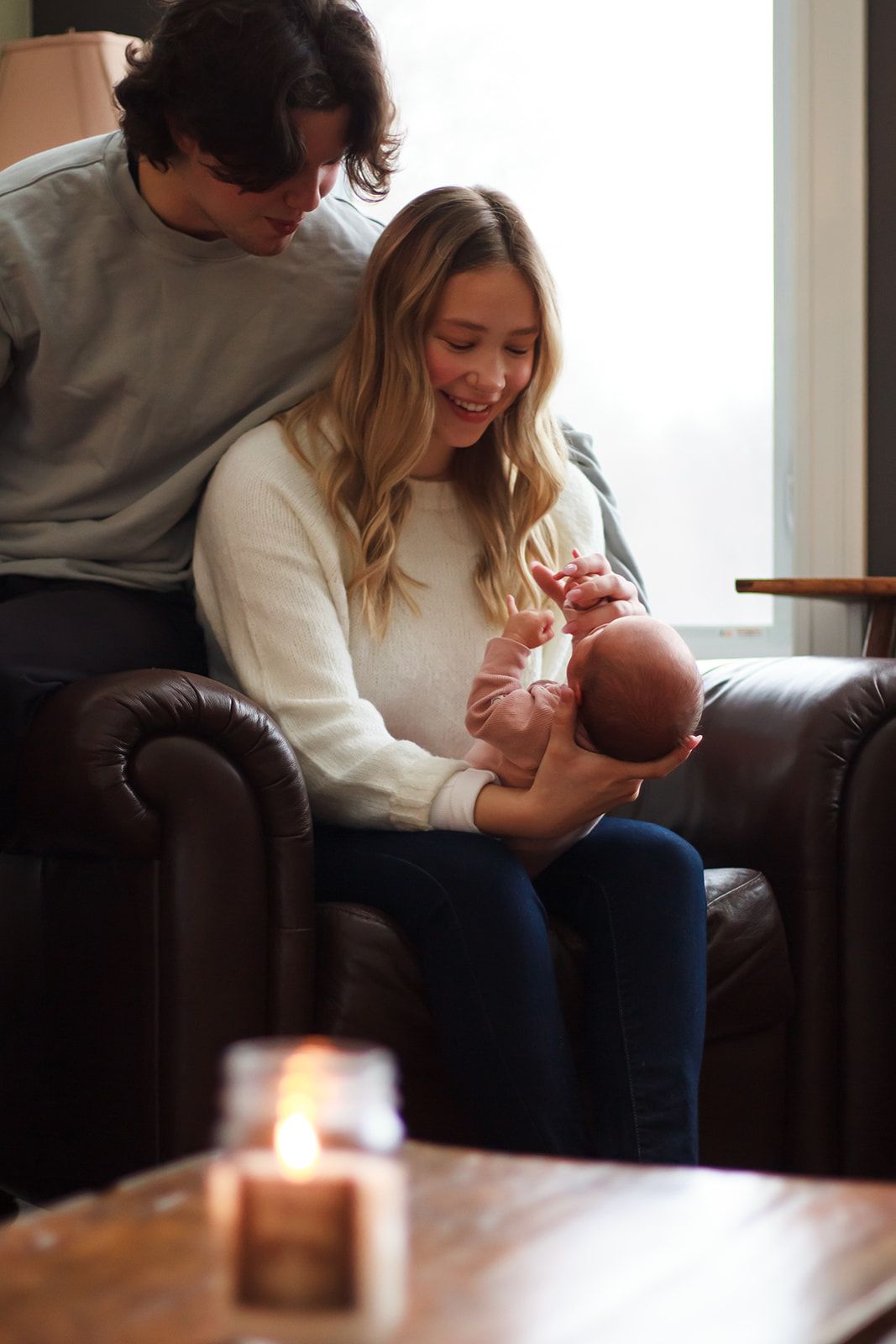 New parents smiling at newborn during in home lifestyle session.