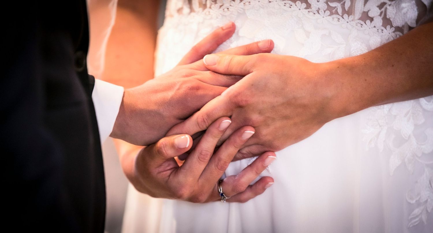 Close-up of hands exchanging rings during wedding ceremony.