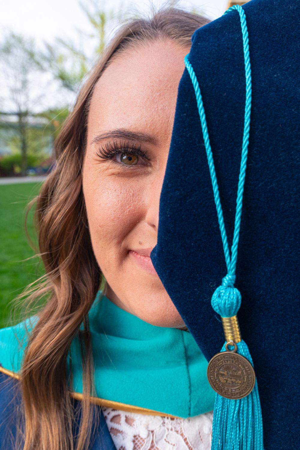 Close-up detail of graduation cap with turquoise tassel and medallion.