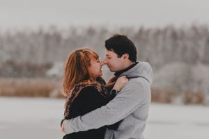 A couple shares an intimate moment in a snowy winter setting.