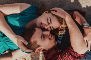 A couple lying close together on a beach sharing an intimate moment in sunlight.
