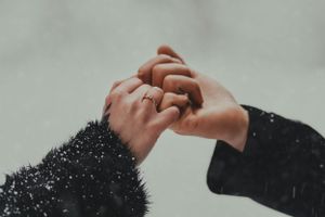 Close-up of hands touching against light background in romantic gesture.