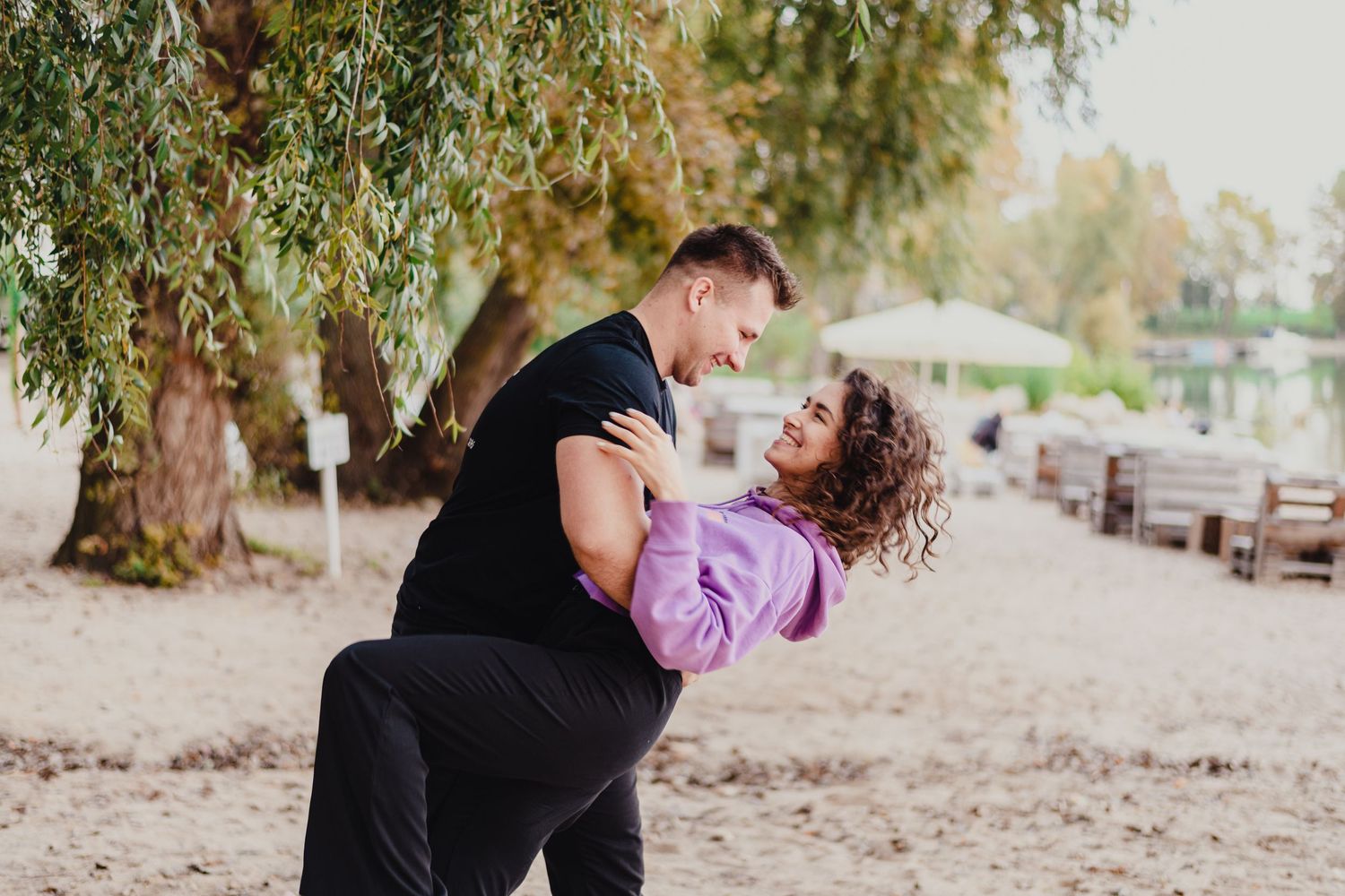 Playful couple dancing and twirling in outdoor setting.