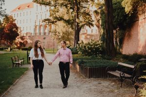 Two people walk together on an autumn path lined with golden trees.