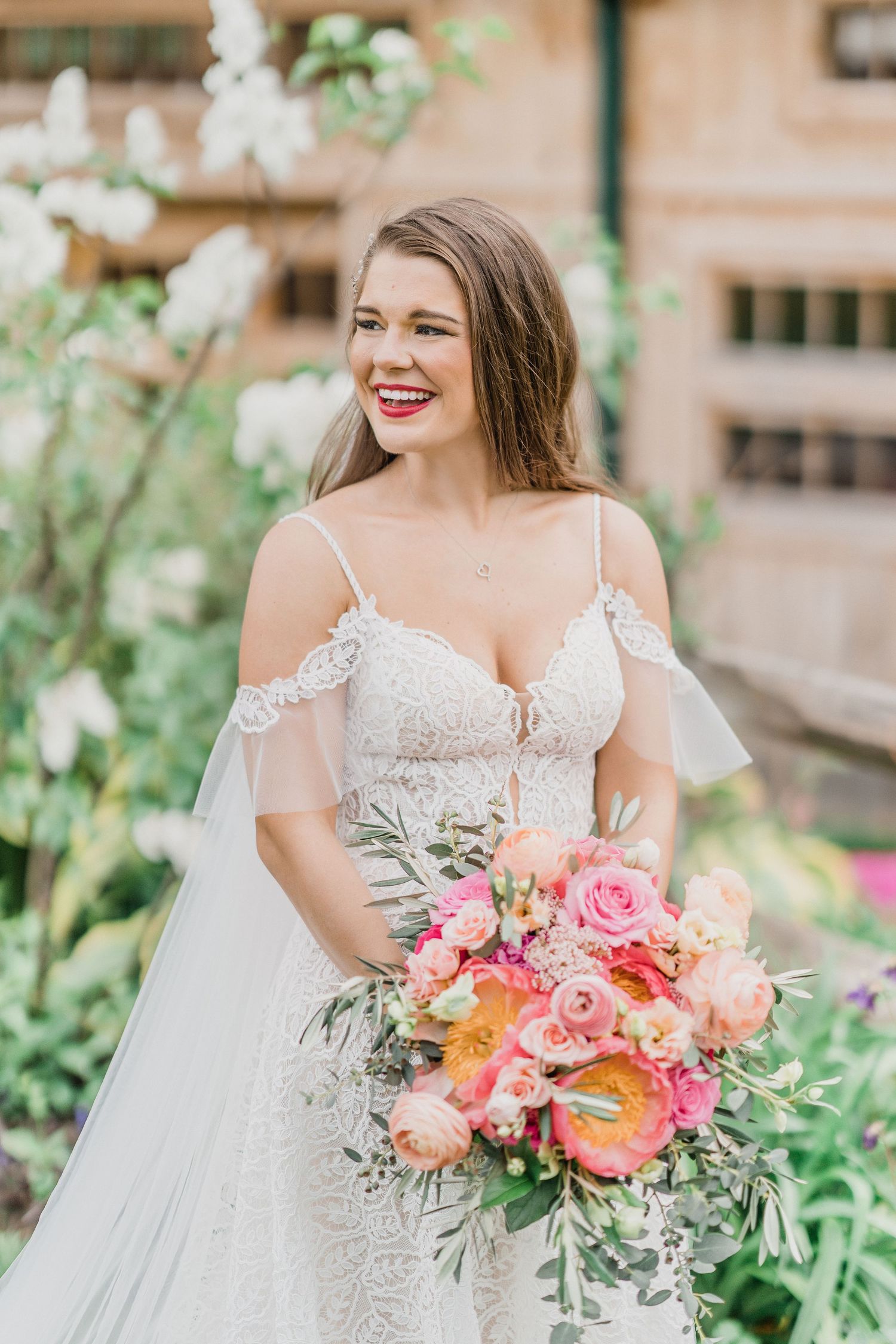 Bride in white gown looking to the side and smiling holding bouquet of bright pink flowers by NH wedding photographer