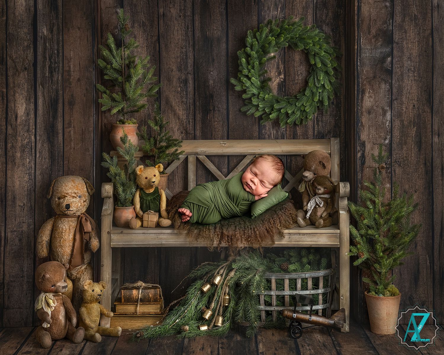 Christmas themed newborn photo with rustic decor, wreaths, and stuffed animals on wooden backdrop.