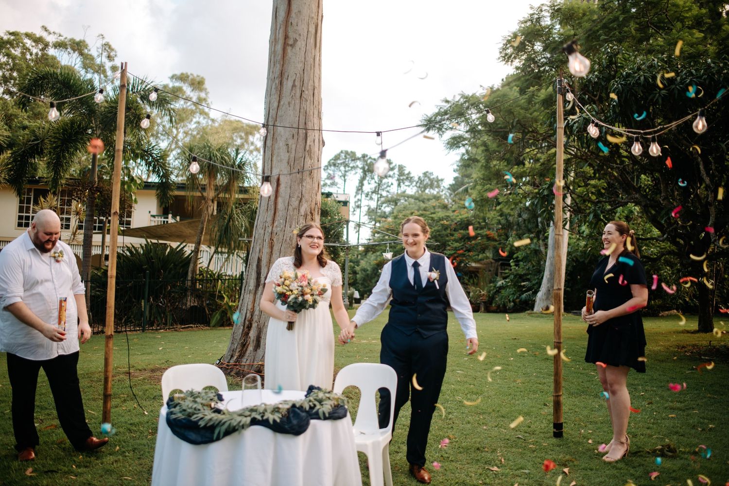 Wedding ceremony setup in garden with string lights and signing table.