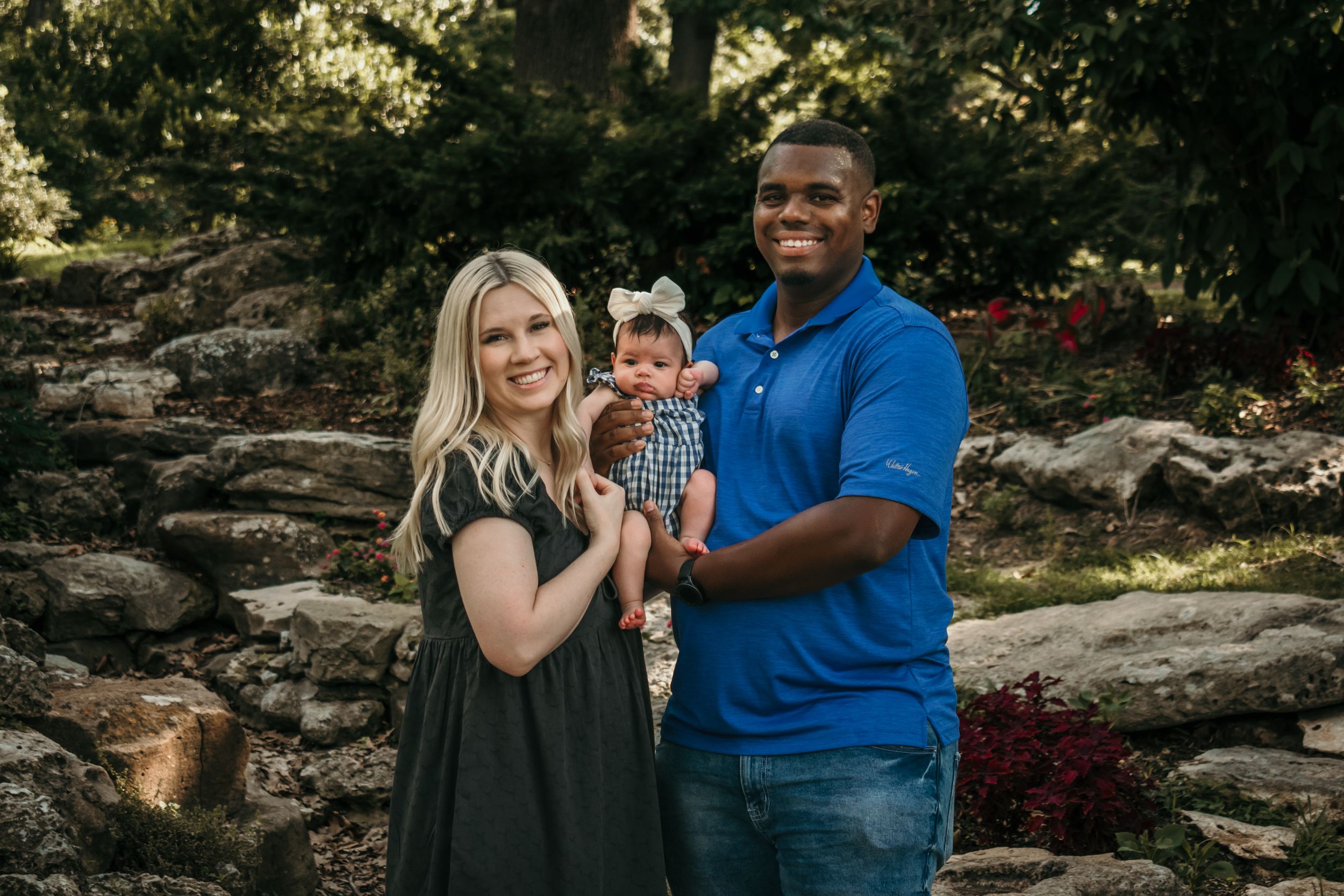 A lovely couple smiles wide as they pose with their newborn