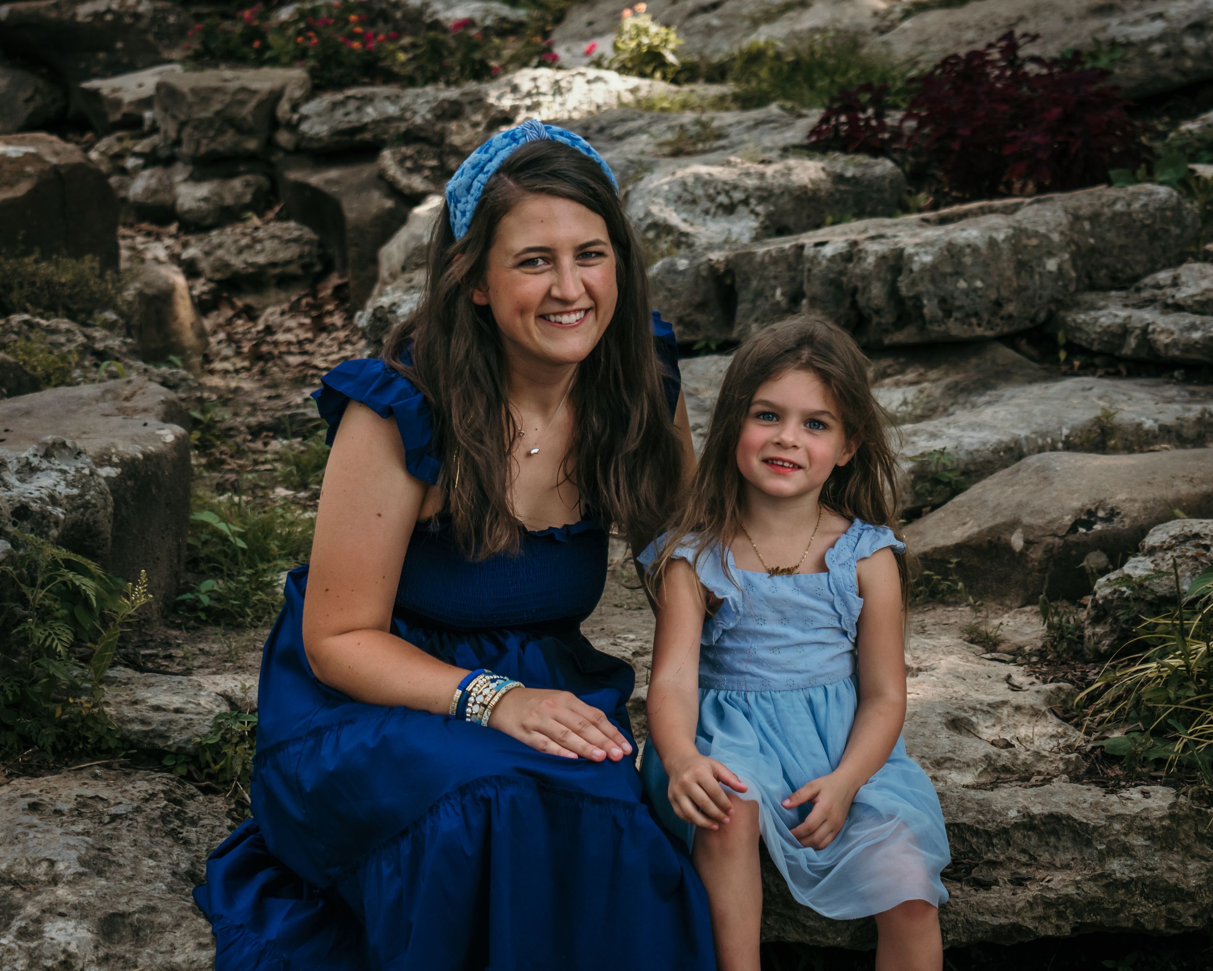 A young mom and her daughter take a break on an outcropping of rocks