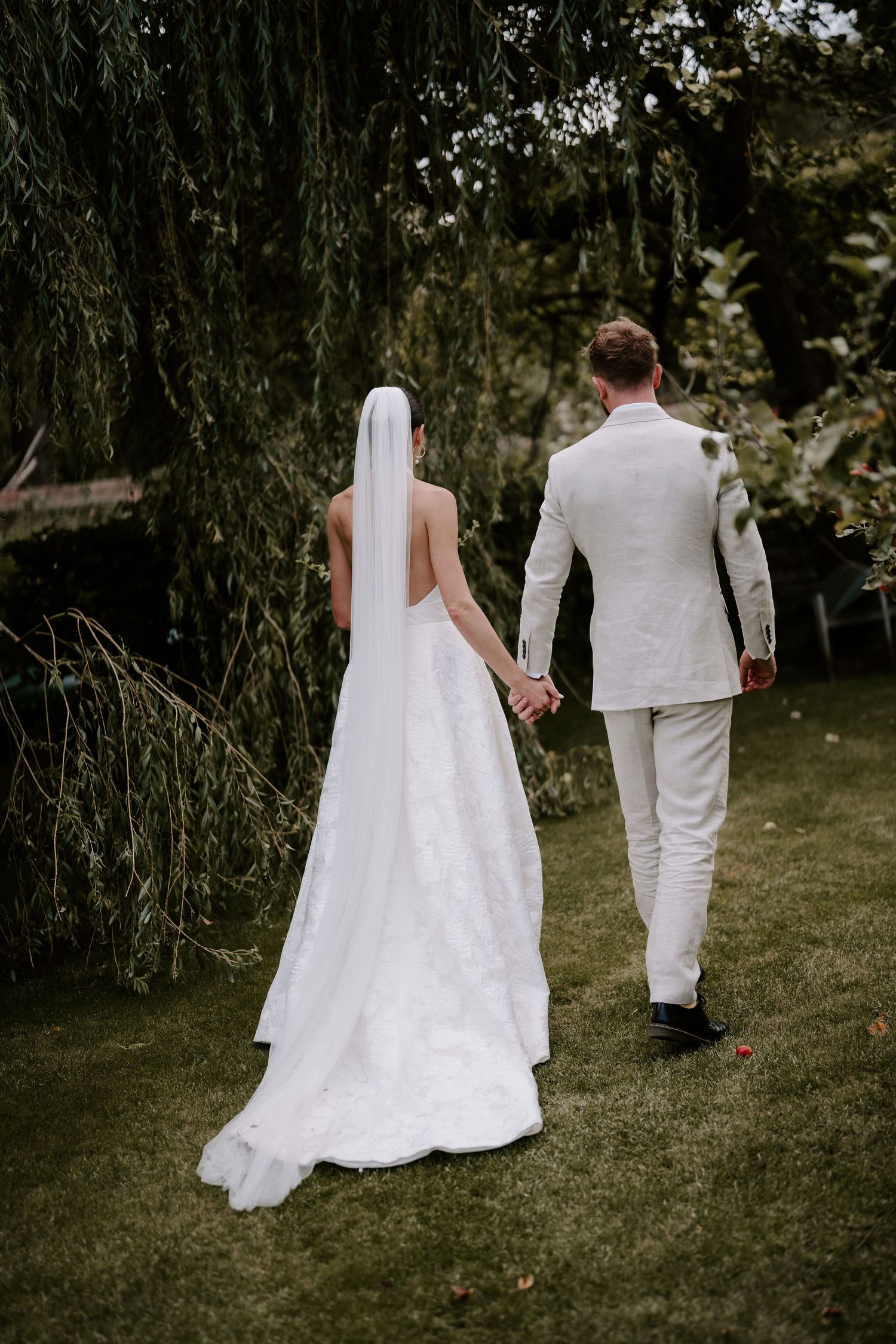 bride and groom walking under willow tree in islip, oxfordshire