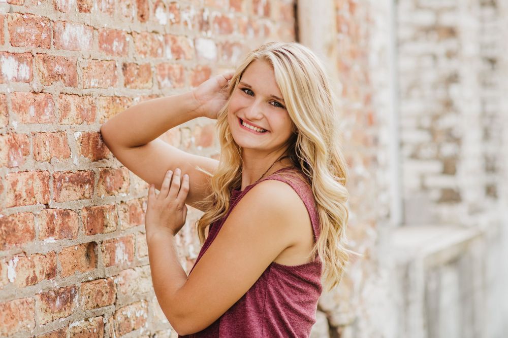 Lifestyle portrait against rustic brick wall in casual summer attire.