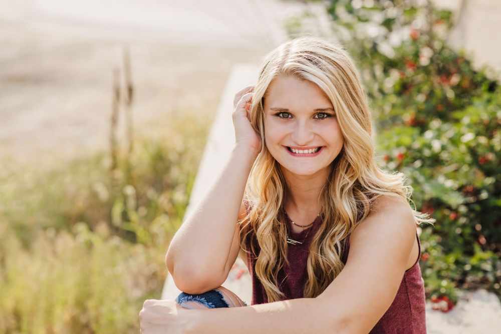 Casual outdoor portrait with natural background and burgundy top.
