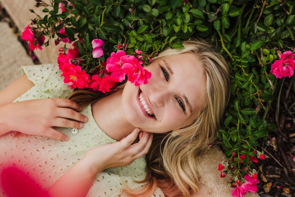 Portrait session with bright pink flowers and natural greenery.