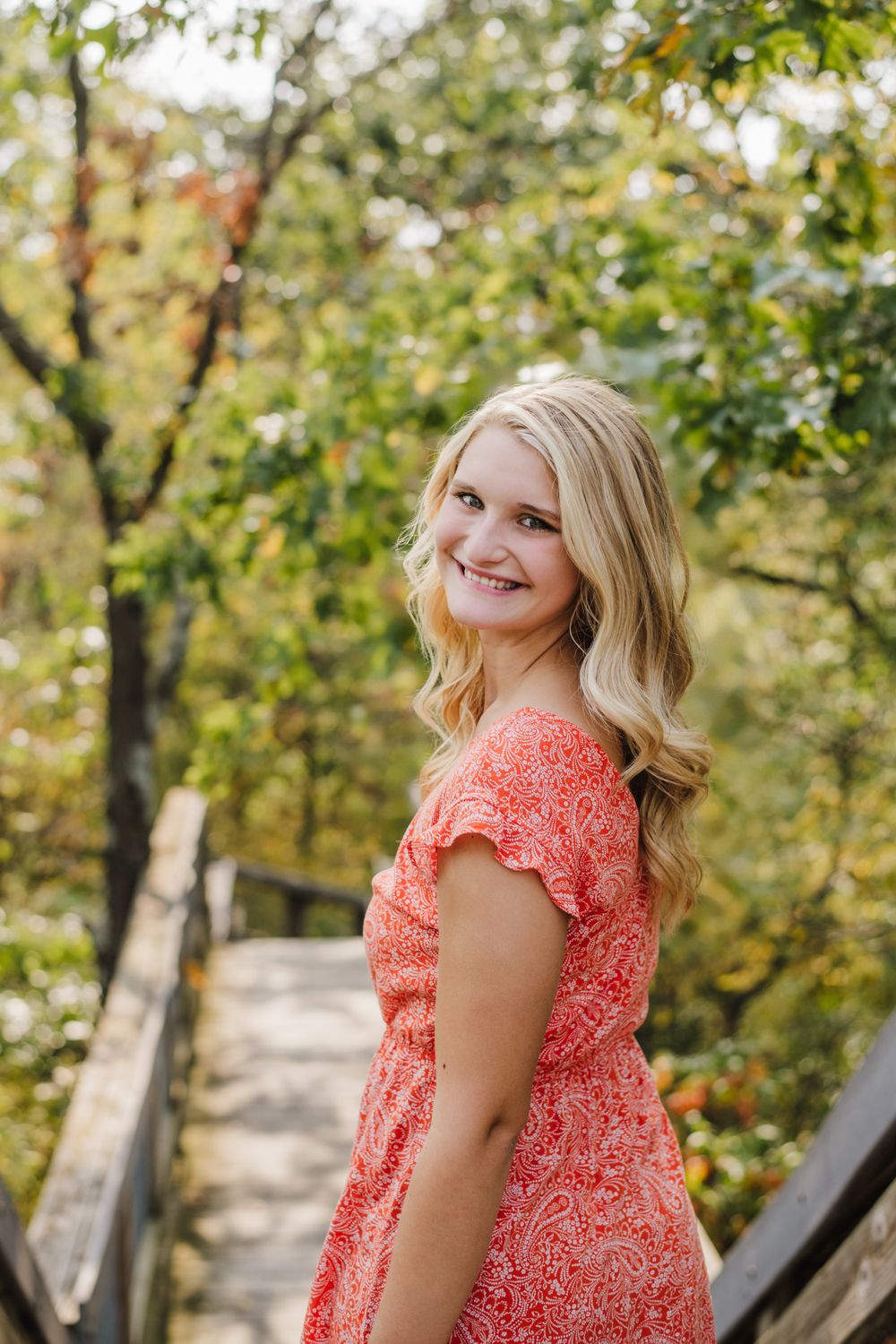 Outdoor portrait session in coral dress with natural autumn scenery.