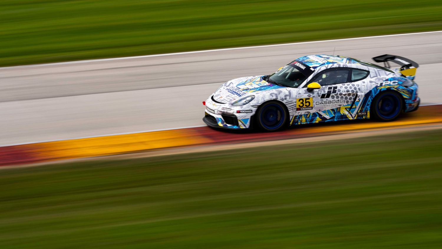 Multiple race cars navigate a green-bordered racetrack during a high-speed competition.