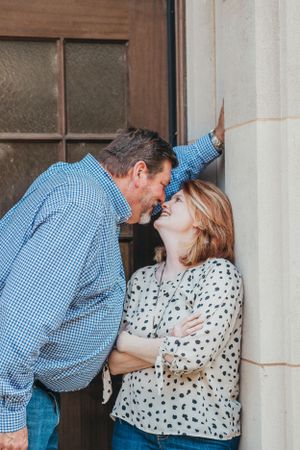 Couple sharing a romantic moment against white wall with vintage windows.