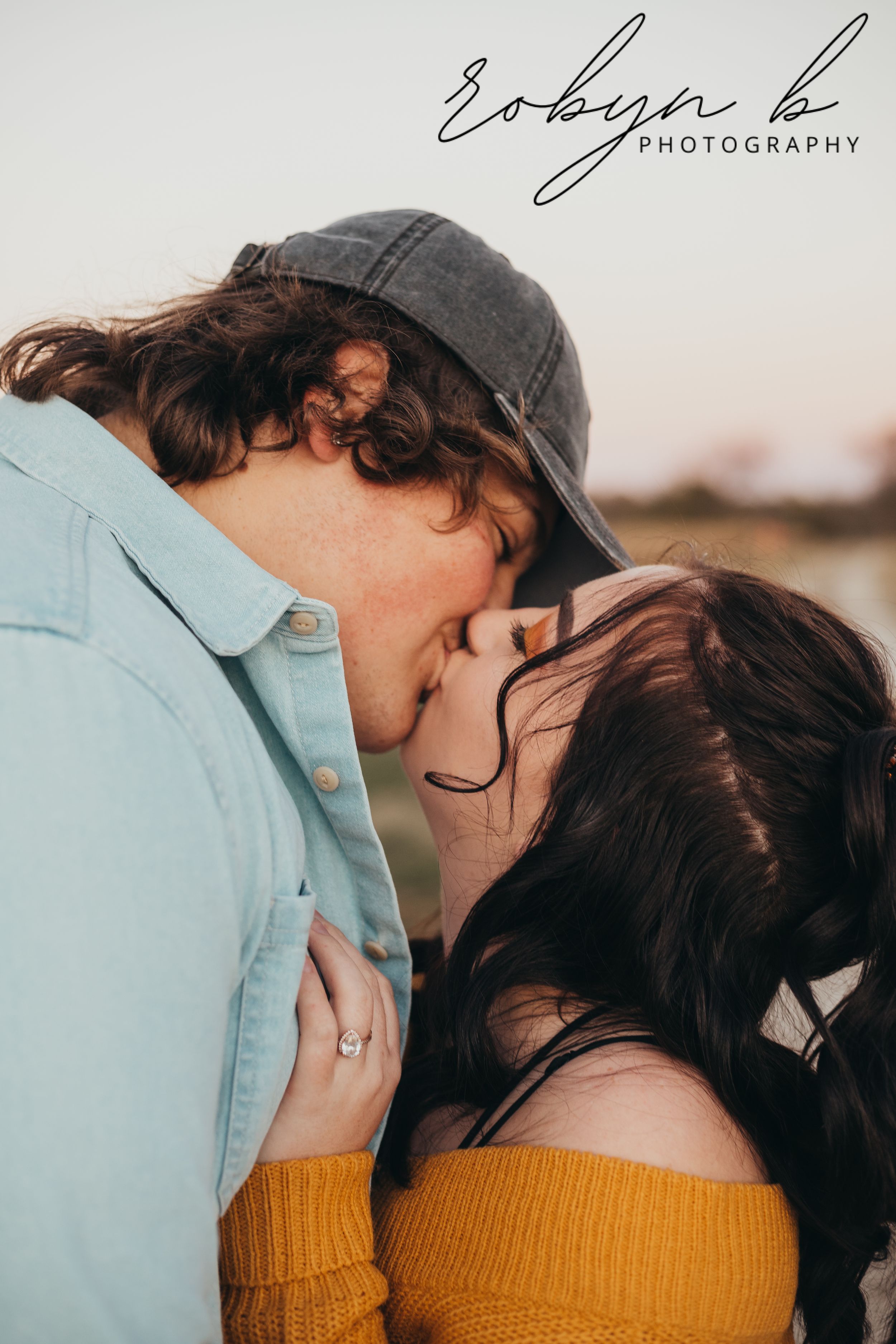Romantic outdoor photoshoot showing couple in blue shirt and yellow top embracing in soft golden light.