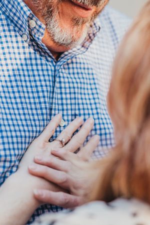 Close-up detail of blue gingham shirt and hands showing emotional connection.