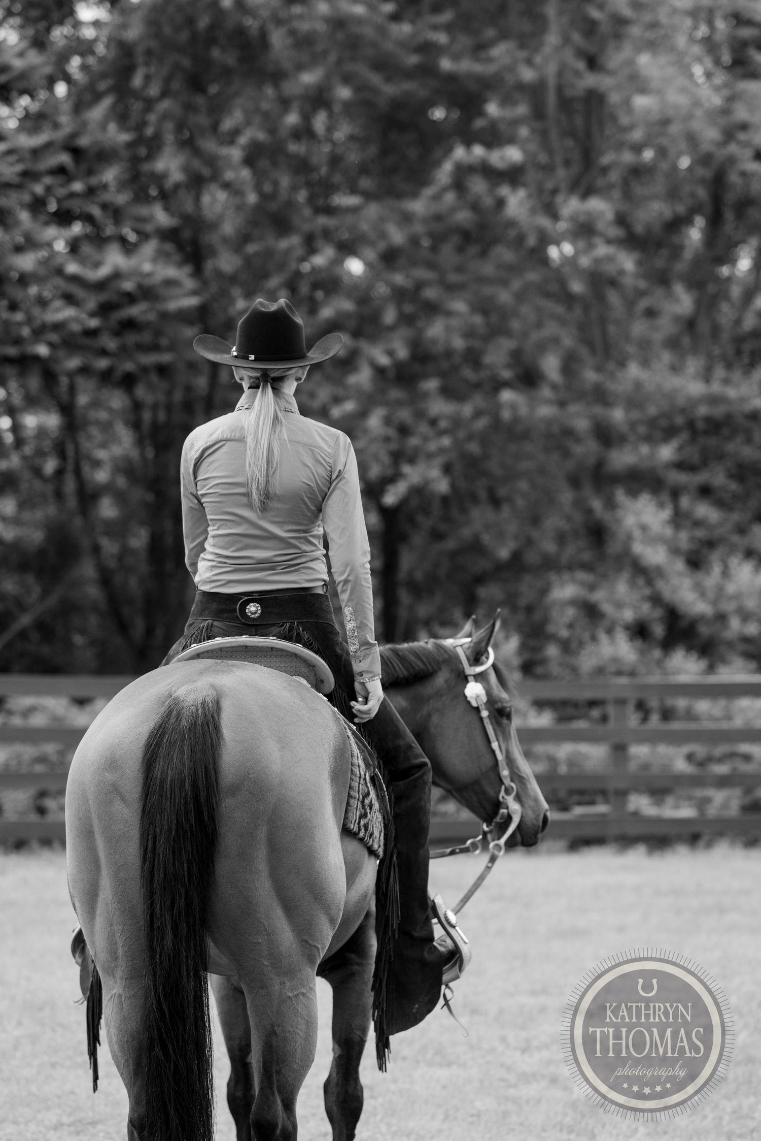 Back view of western rider on horseback in black and white photography.