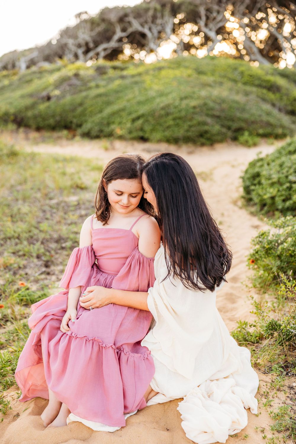 A tender moment between parent and child on a coastal path at golden hour.