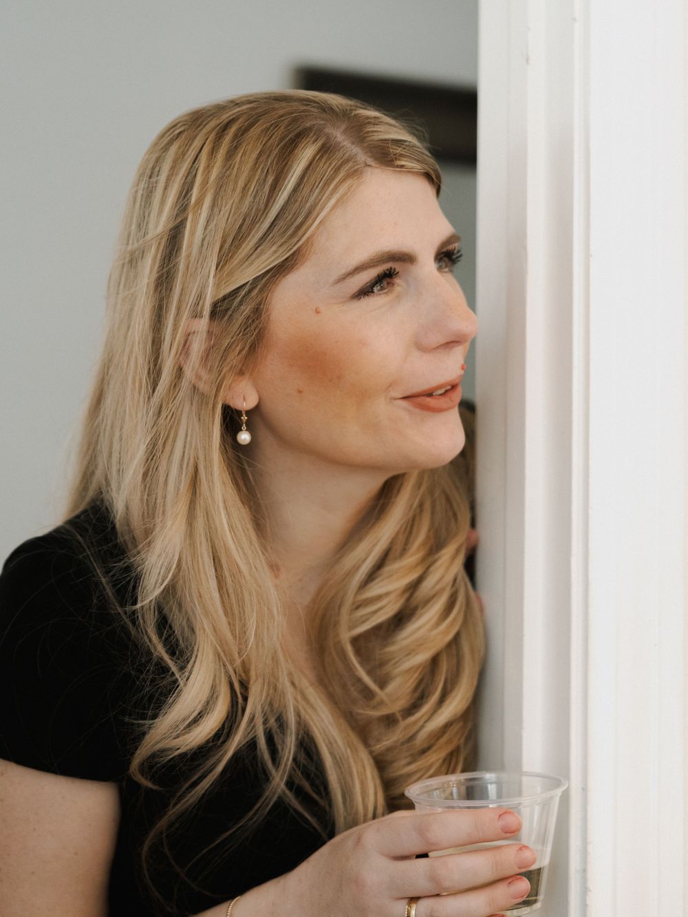 Woman with blonde hair holding a glass while looking to the side in an elegant portrait series.