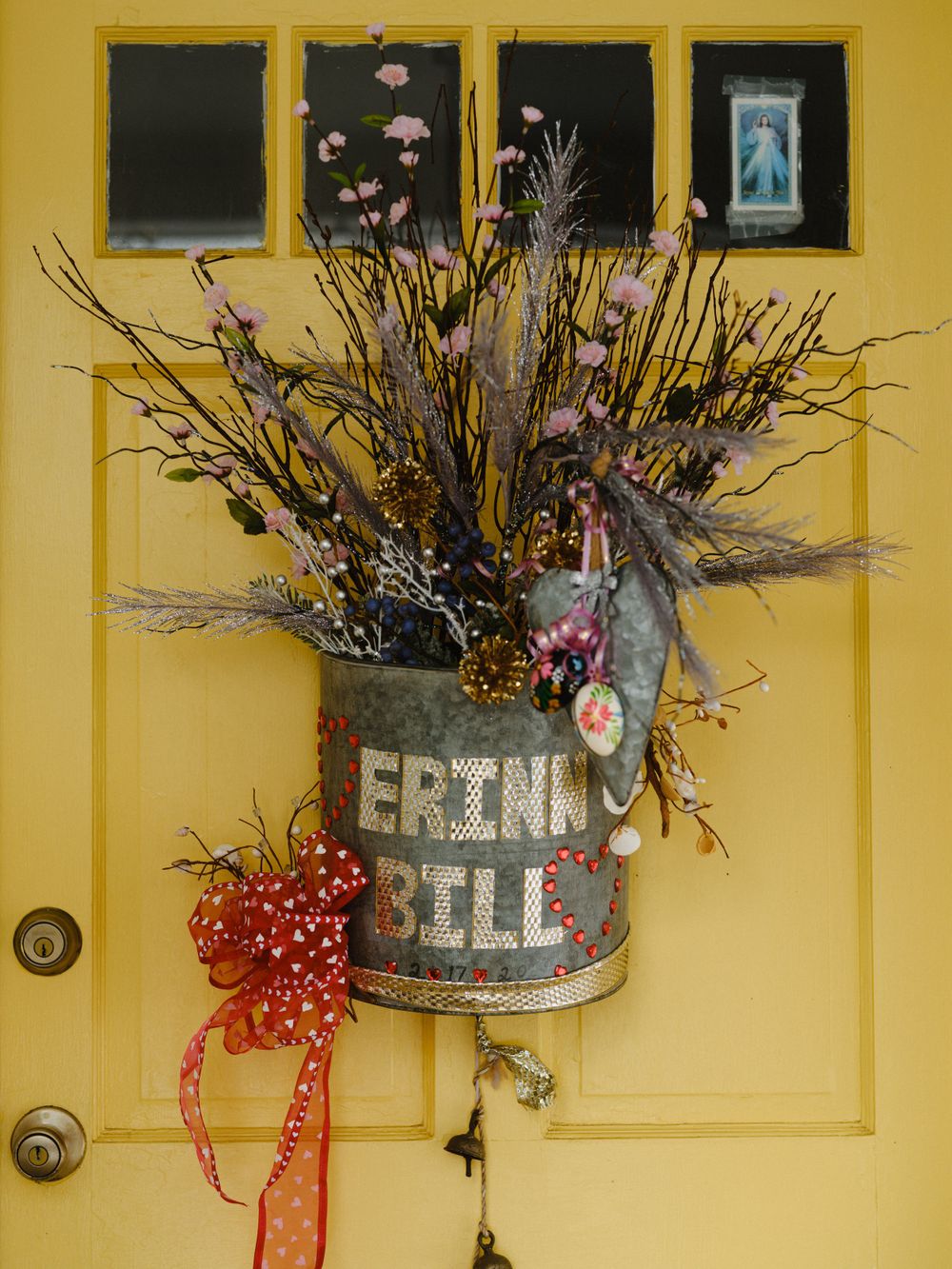 Rustic decorative buckets with dried flowers mounted on a yellow wall.