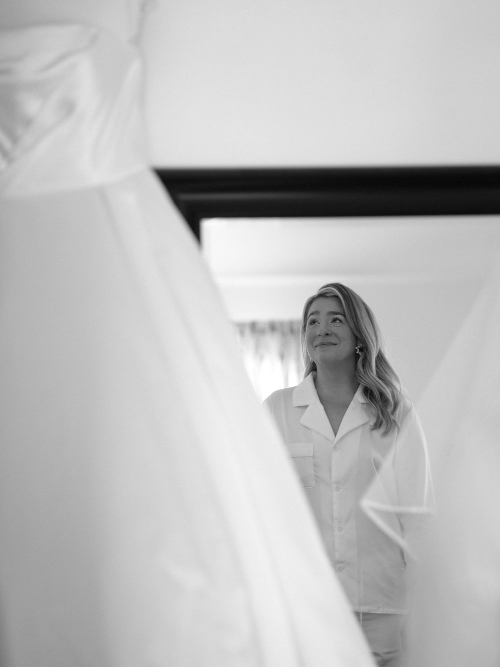 Artistic black and white bridal preparation photo through sheer fabric.
