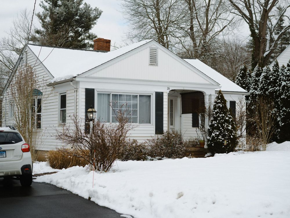 Snow covered ranch-style houses in winter with white siding and driveways.