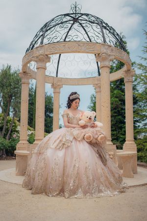 Elegant ball gown photographed under a decorative stone gazebo with wrought iron dome.