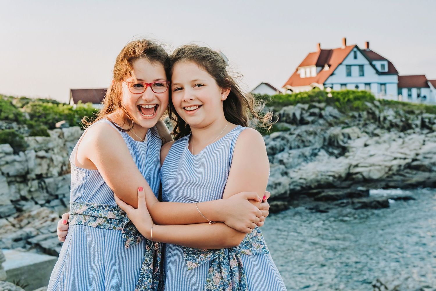 Two sisters embrace during a photo session in front of the Portland Head Light Lighthouse at Fort Williams Park.