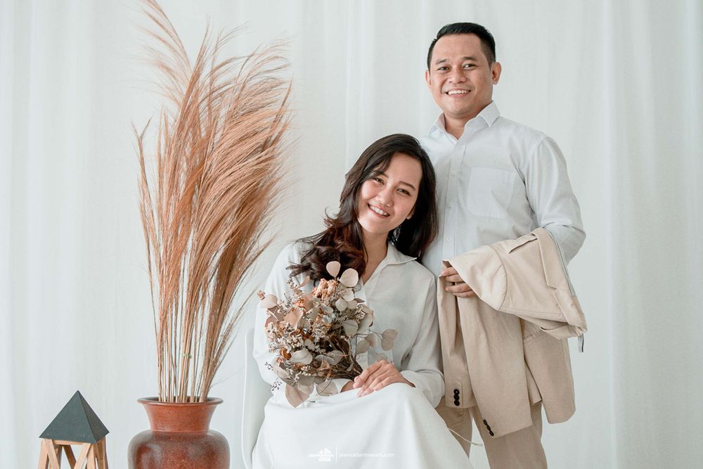 A couple poses for a portrait with dried flowers and pampas grass decor in a minimalist setting.