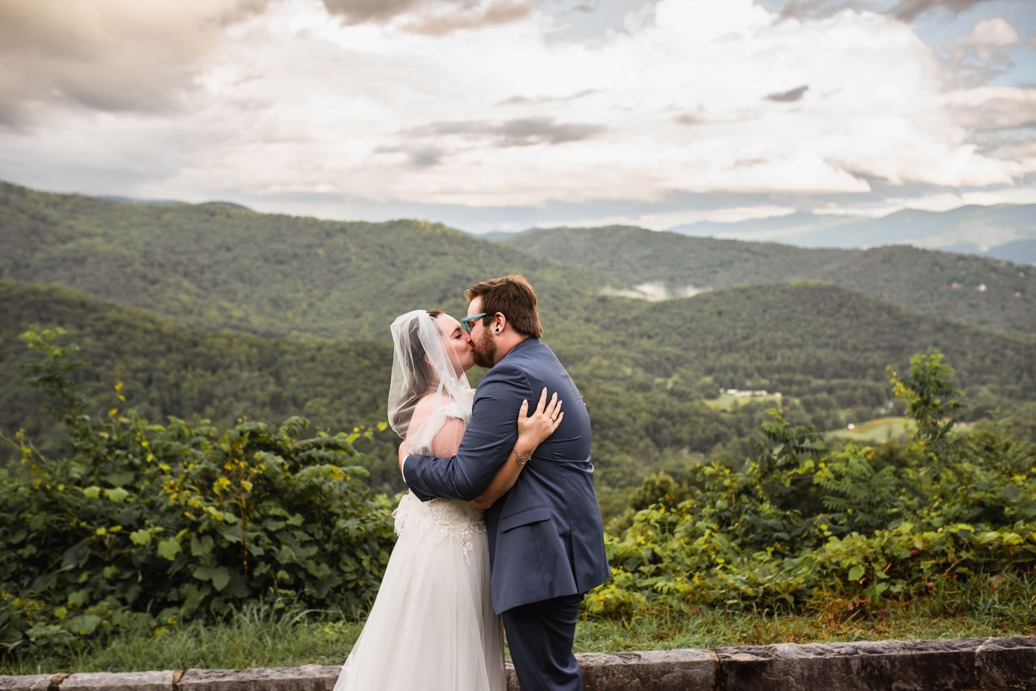 Man and woman kiss with Blue Ridge Mountains behind them during elopement ceremony in Asheville.