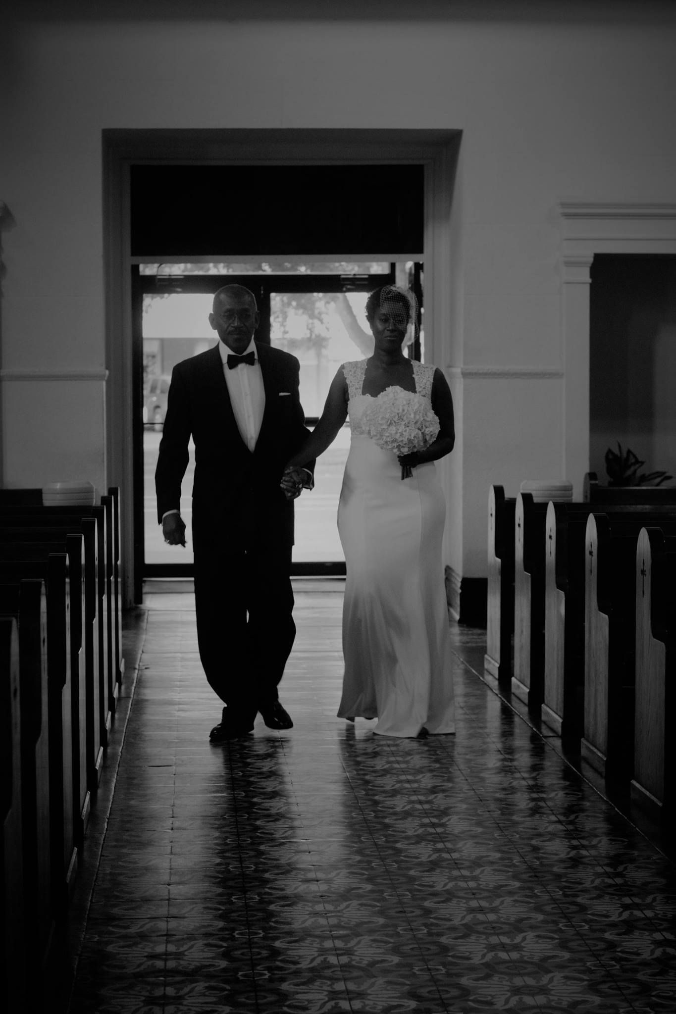 Black and white photo of wedding couple walking down church aisle.