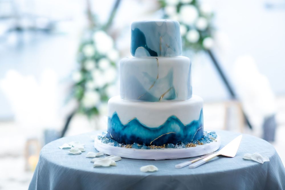 Elegant three-tier wedding cake decorated in white and blue watercolor design.