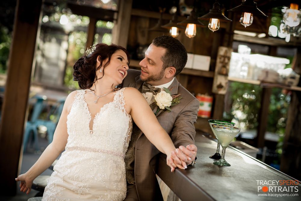 Candid moment at bar with couple in wedding attire sharing a laugh.