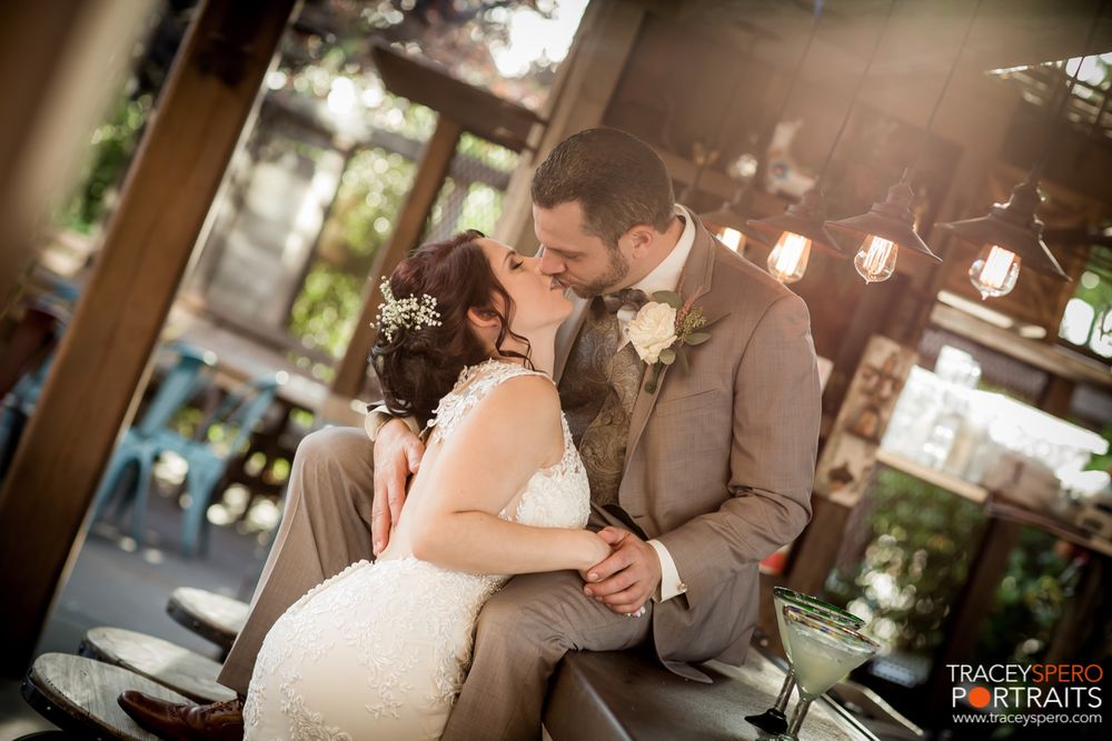 Couple shares intimate moment during outdoor wedding with string lights in background.