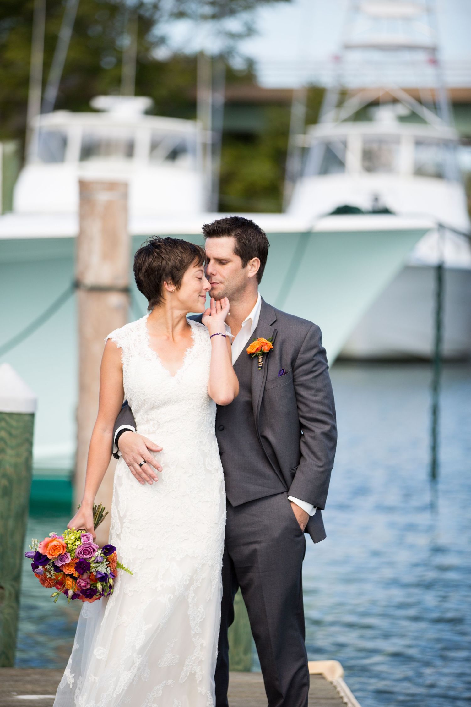 A waterfront wedding scene with boats docked in the marina background.
