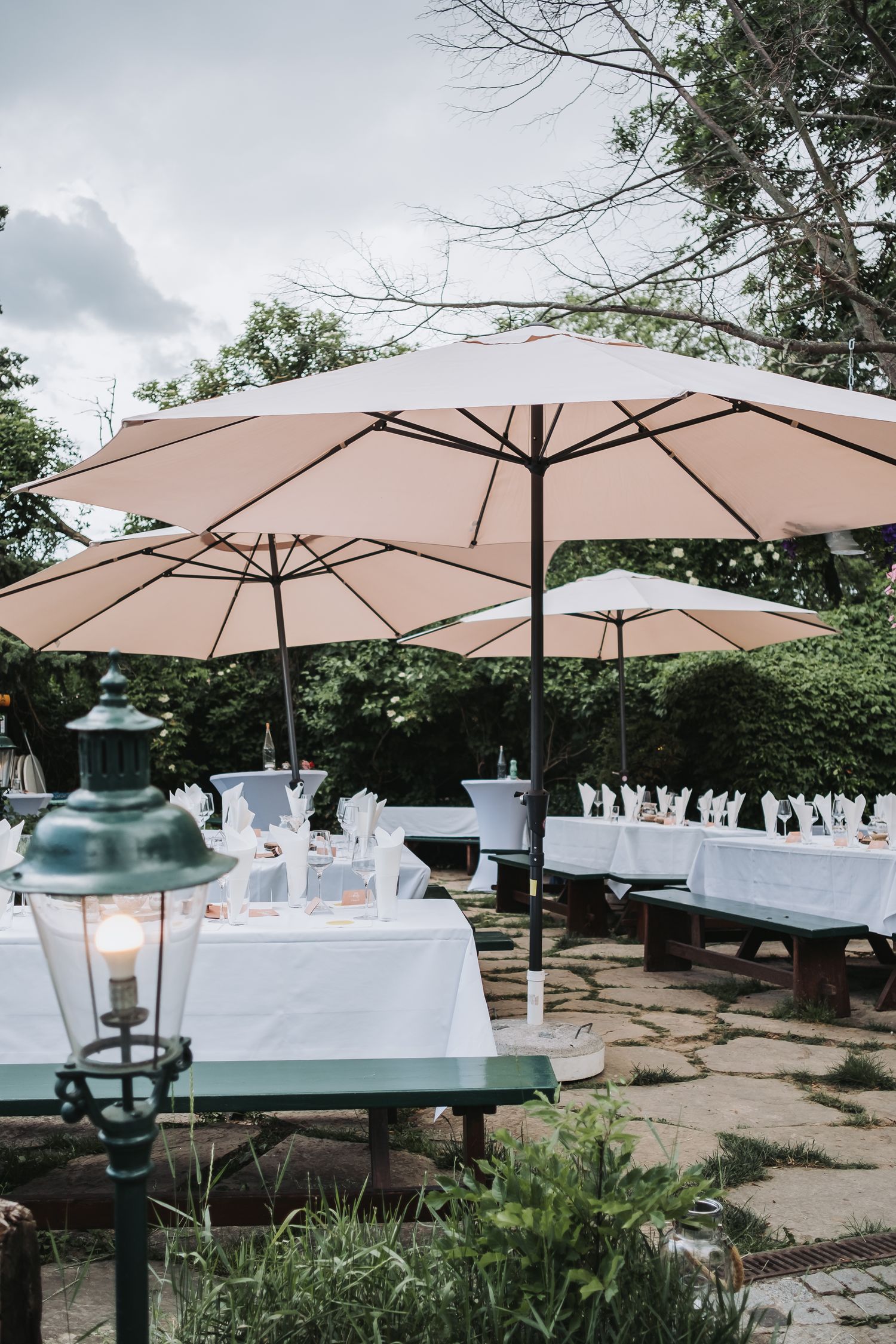 Outdoor wedding reception setup with white umbrellas and elegant table settings.