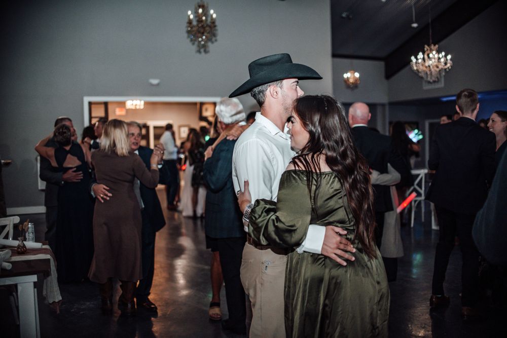 Couples slow dancing at wedding reception under crystal chandeliers.