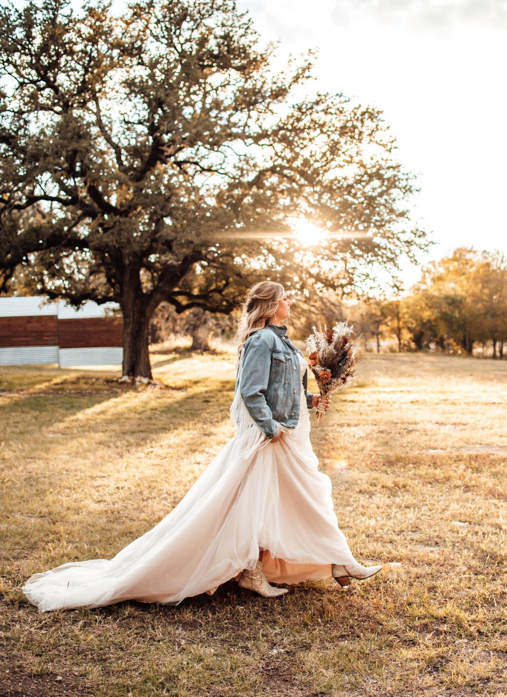 Sunset wedding portraits in field with dramatic golden light and flowing dress.