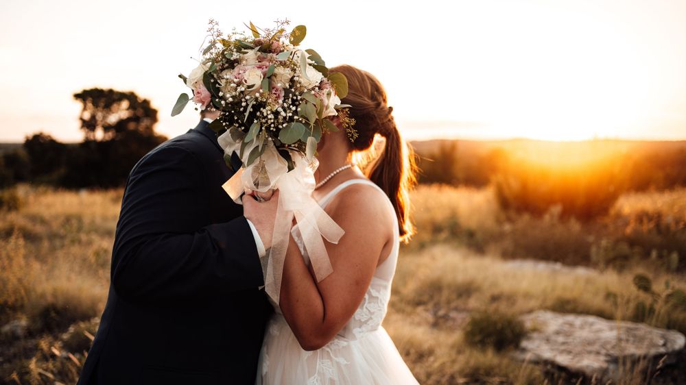 A couple shares an intimate moment during golden hour in a rustic outdoor setting.