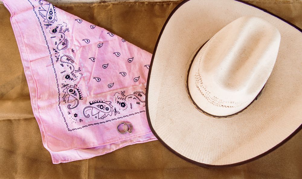 Western-themed wedding decor featuring pink bandanas and a beige cowboy hat.