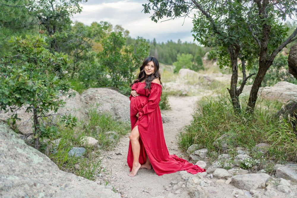 A flowing red dress silhouettes against a natural rock and tree landscape.
