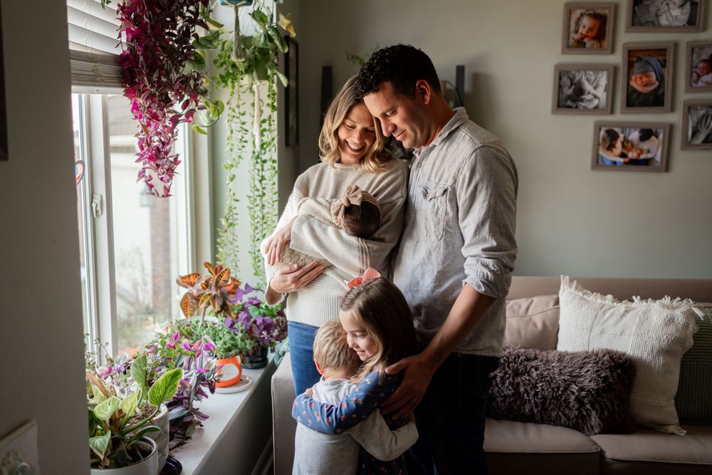 Family sharing tender moment together by window with hanging plants and home decor.