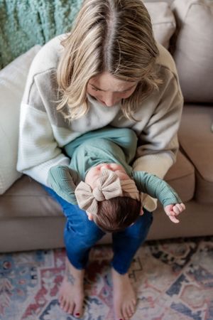 Overhead view of parent and baby sharing special moment on patterned rug.